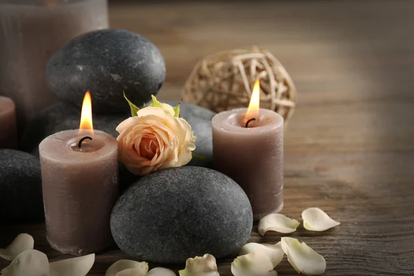 Hermosa composición relajante de velas encendidas, guijarros y flores sobre fondo de madera — Foto de Stock