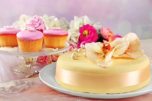 Kuchen mit Zuckerpaste Blumen und Cupcakes, auf hellem Hintergrund — Stockfoto