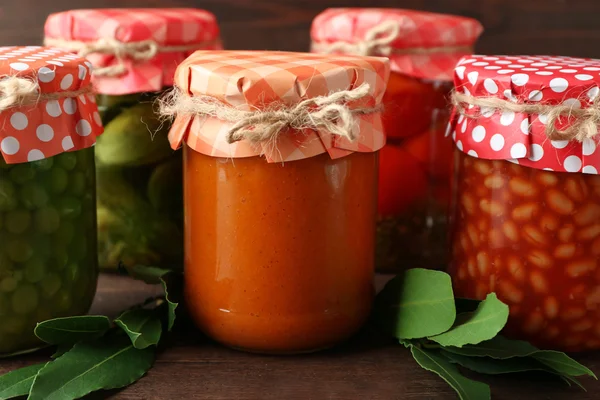 Frascos con verduras y frijoles en vinagre sobre fondo de madera —  Fotos de Stock