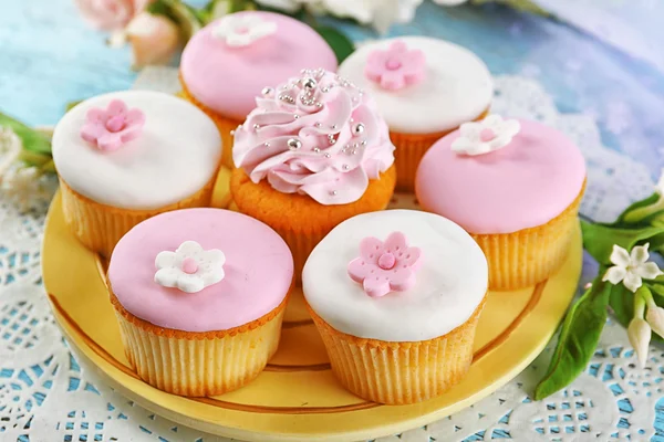 Leckere Cupcakes auf Teller, auf farbigem Holzhintergrund — Stockfoto