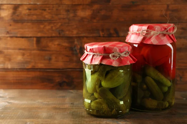 Jars with pickled vegetables on wooden background