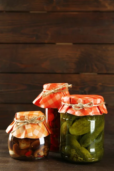 Potten met gepekelde groenten en champignons op houten ondergrond — Stockfoto