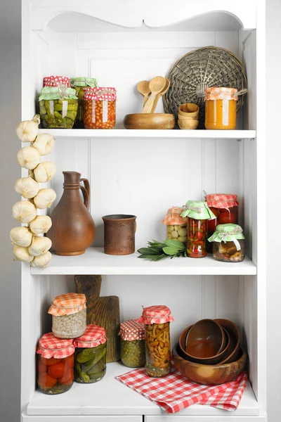 Jars with pickled vegetables and beans, spices,  kitchenware and utensils on shelf — Stock Photo, Image