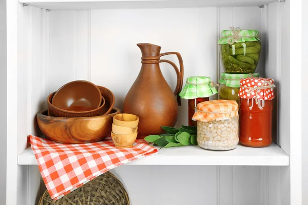 Potten met ingemaakte groenten en keukengerei op plank — Stockfoto