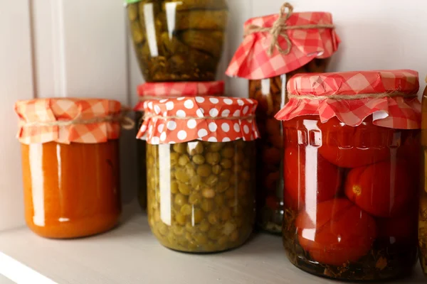 Jars with pickled vegetables and beans on wooden shelf — Stock Photo, Image