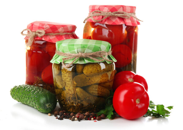 Jars of canned tomatoes and cucumbers isolated on white
