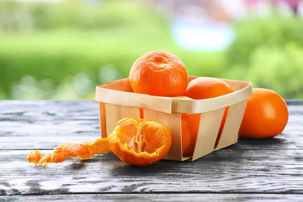 Ripe tangerines on wooden table against blurred nature background — Stock Photo, Image