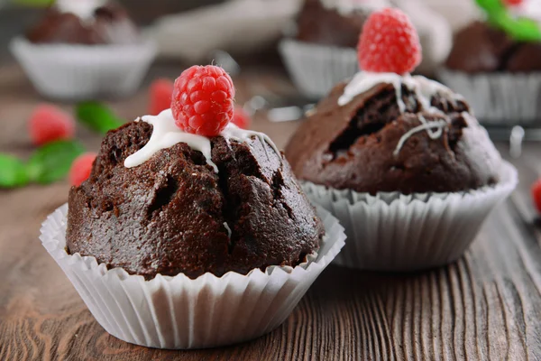 Delicious chocolate cupcakes with berries and fresh mint on wooden table close up — Stock Photo, Image