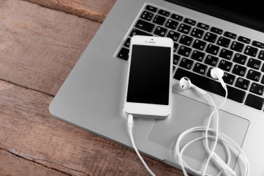 Kulaklıklarla laptop ahşap arka plan üzerinde beyaz cep telefonu
