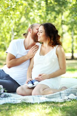 Yakışıklı adam ve hamile eşi ile parkta mavi bebek patik