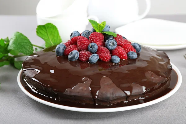 Köstlicher Schokoladenkuchen mit Sommerbeeren auf grauer Tischdecke, Nahaufnahme — Stockfoto