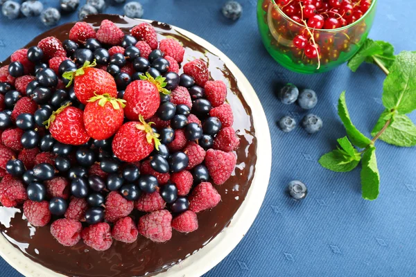 Delicious chocolate cake with summer berries on blue tablecloth, closeup — Stock Photo, Image