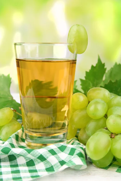 Bicchiere di succo d'uva sul tavolo con tovagliolo a quadretti su sfondo sfocato chiaro — Foto Stock