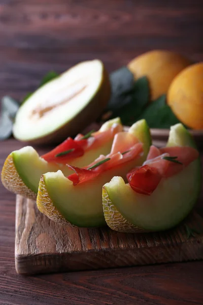 Melone mit Parmaschinken auf Holztisch, Nahaufnahme — Stockfoto