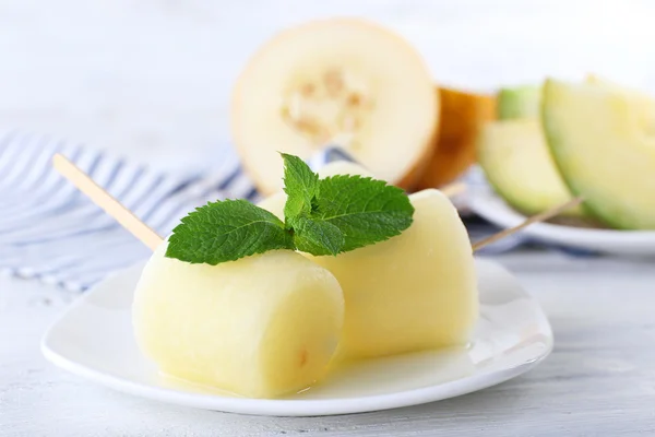 Melon lody na patyku na drewnianym stole, zbliżenie — Zdjęcie stockowe