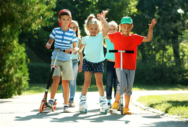 Crianças andando em scooters e patins — Fotografia de Stock