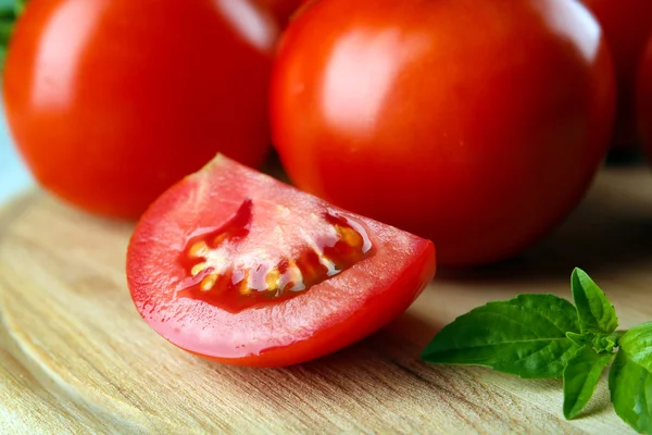 Červená rajčata na kulaté dřevěné krájecí deska closeup — Stock fotografie