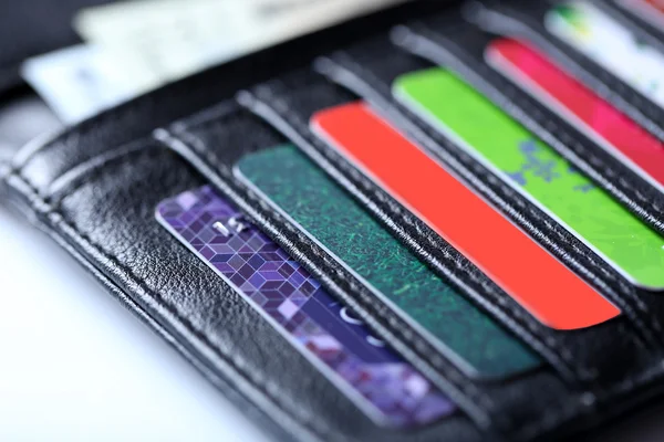 Zwarte lederen portefeuille met kleurrijke creditcards en geld, close-up — Stockfoto