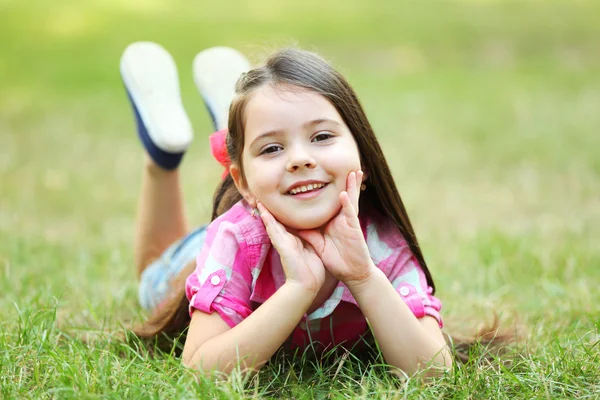 Gadis kecil yang bahagia di rumput hijau di taman — Stok Foto