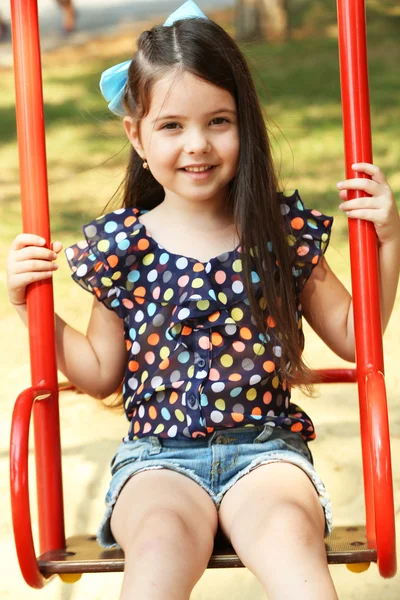 Happy little girl riding swings — Stock Photo, Image