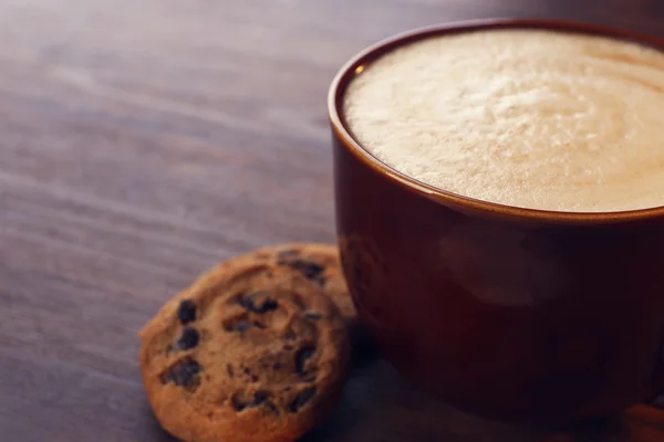 Cup of coffee with milk foam and  cookies with chocolate crumbs on wooden background — Stock Photo, Image