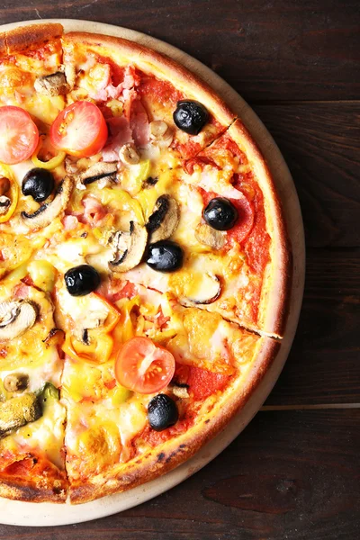 Pizza on cutting board on wooden background — Stock Photo, Image