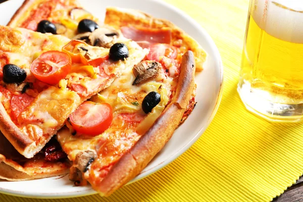 Sliced pizza served with beer on wooden table — Stock Photo, Image