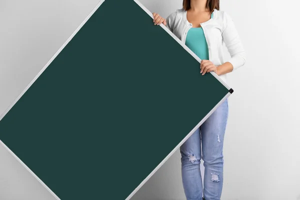Žena v kauzální s zelená tabule na šedém pozadí, zblízka — Stock fotografie