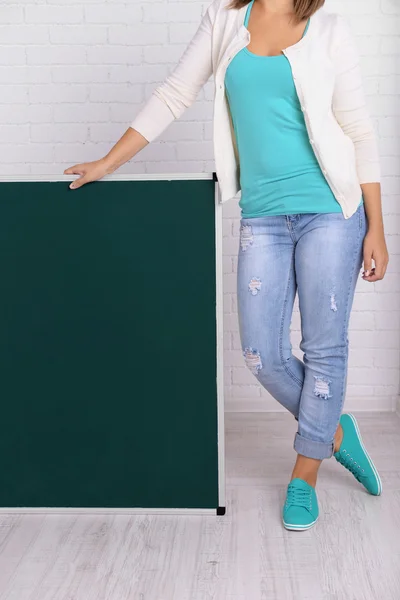 Woman in causal with green blackboard against brick wall, close up — Stock Photo, Image