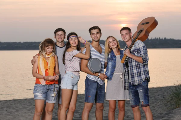 Happy friends having fun on river and sky background at sunset