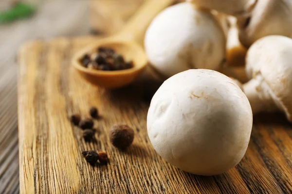 Champignon mushrooms, a spoon and spices on wooden background — Stock Photo, Image