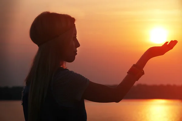 Mujer sosteniendo el sol en las manos al atardecer — Foto de Stock