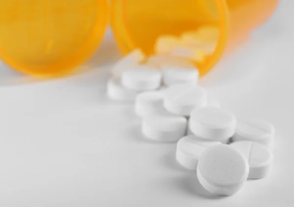 Blauwe drugs gemorst uit geel pil fles op een witte achtergrond, close-up — Stockfoto