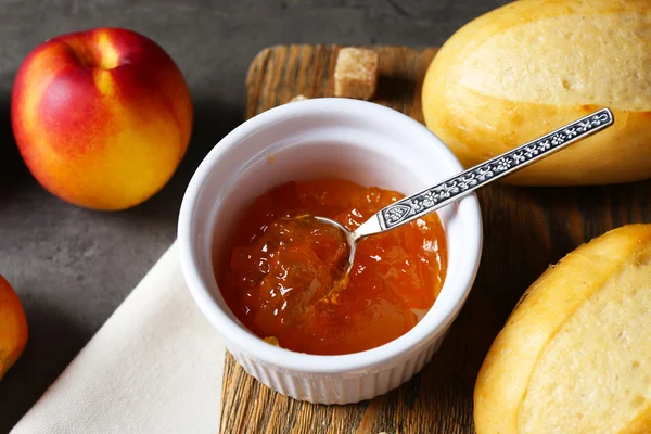 Tasty jam in the bowl, ripe peach, crackers and fresh buns close-up — Stock Photo, Image