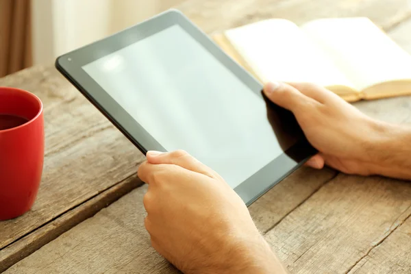 Adamın elleri, kitap ve ahşap masa üzerinde çay tablet — Stok fotoğraf