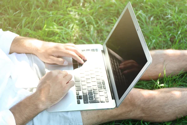 Man with laptop sitting on green grass in the park, close up — Stock Photo, Image