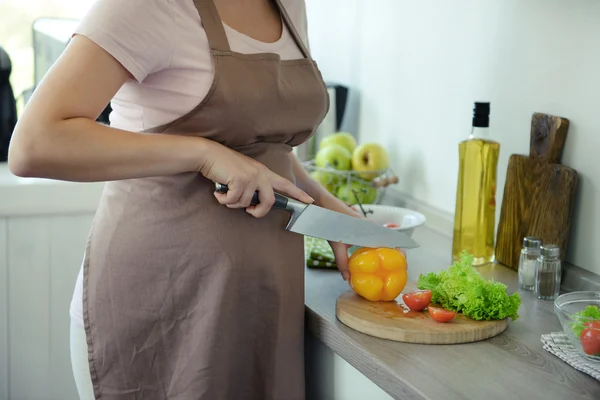Привлекательная беременная женщина режет овощи для витаминного салата на кухне — стоковое фото