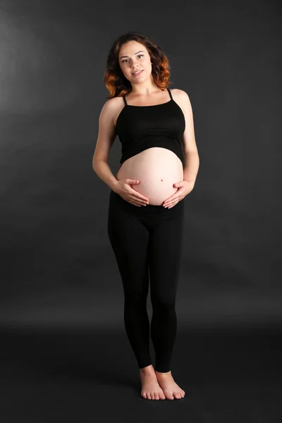 Giovane donna incinta felice su sfondo nero — Foto Stock