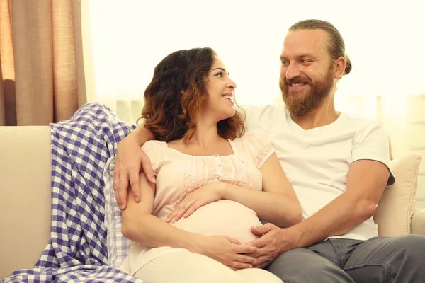 Feliz casal amado em espera para o nascimento do bebê no sofá no quarto — Fotografia de Stock