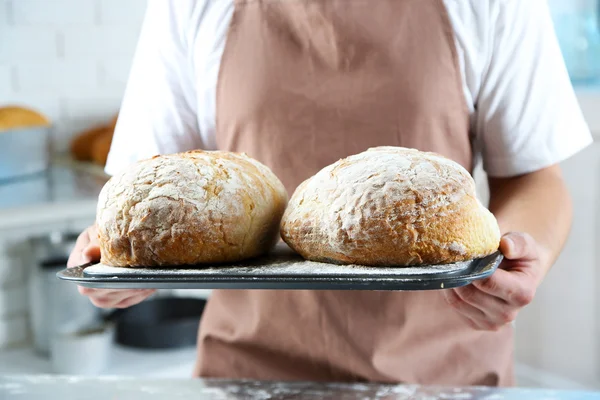 Пекарь проверяет свежеиспеченный хлеб на кухне пекарни — стоковое фото