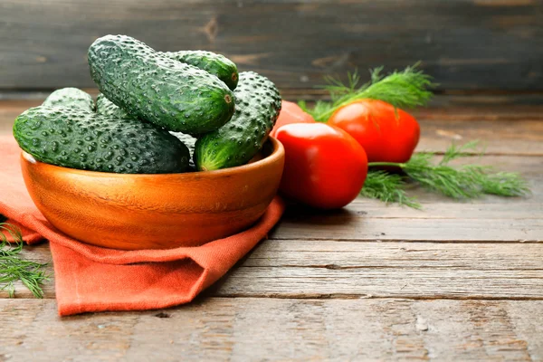 Fresh cucumbers with red cotton serviette and tomatoes on wooden table — Stock Photo, Image