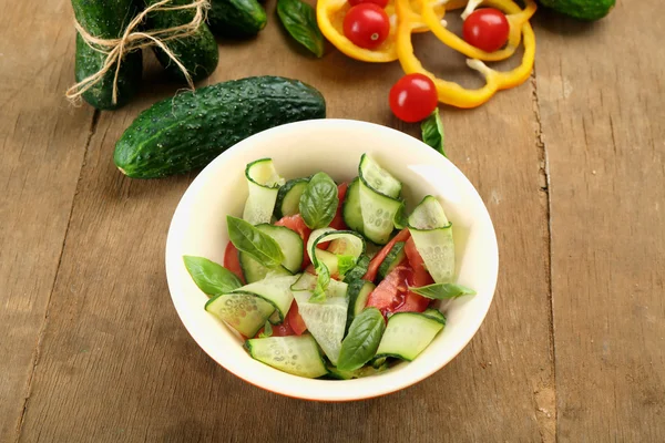 Vegetable salad with cucumbers on wooden background — Stock Photo, Image