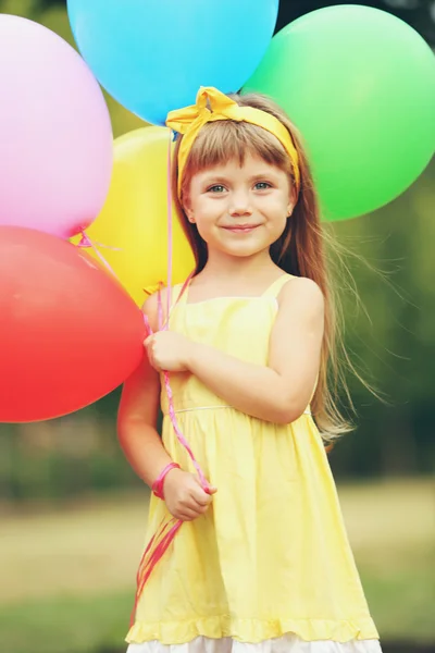 Liten flicka med ballonger utanför — Stockfoto