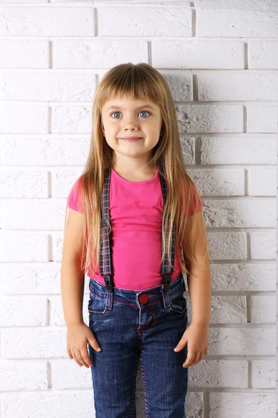 Hermosa niña en fondo de pared de luz — Foto de Stock