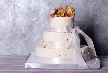 Düğün pastası gri arka plan üzerine çiçeklerle dekore edilmiş