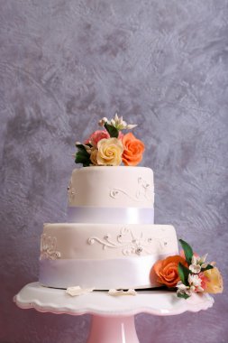 Çiçekli pembe ahşap masa gri arka plan üzerinde beyaz düğün pastası dekore