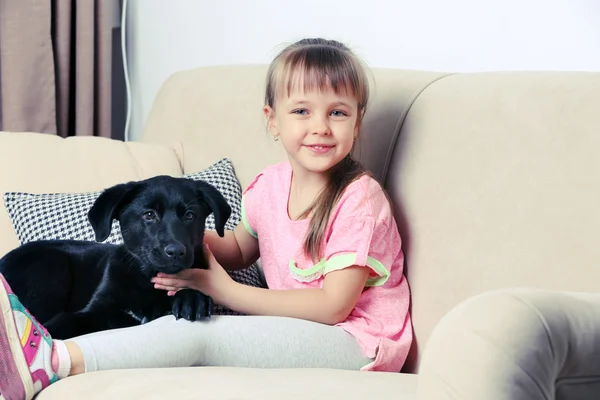 Маленькая девочка с щенком на диване — стоковое фото
