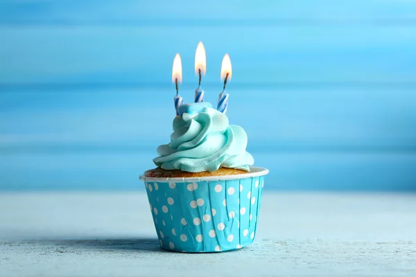 Süße Cupcake mit Kerzen auf blauem Holzhintergrund — Stockfoto