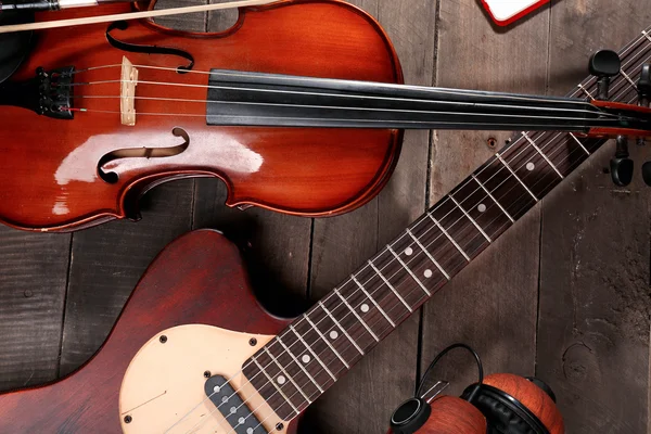 Chitarra elettrica, violino e cuffie su sfondo di legno — Foto Stock