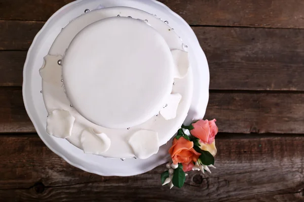 Белый свадебный торт украшен цветами на деревянном фоне — стоковое фото